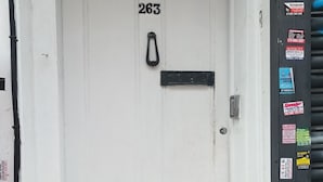 Una porta bianca con il numero 263, una fessura per la posta nera e una maniglia in metallo.