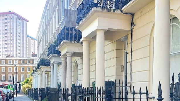 A row of traditional buildings with uniform architecture, a stone-paved street, and a black metal fence. - Spacious Studio Flat - Camden Kings Cross Zone 1 (London)