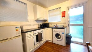 A compact kitchen with a washing machine, a microwave, and a stove. - Spacious Studio Flat - Camden Kings Cross Zone 1 (London)