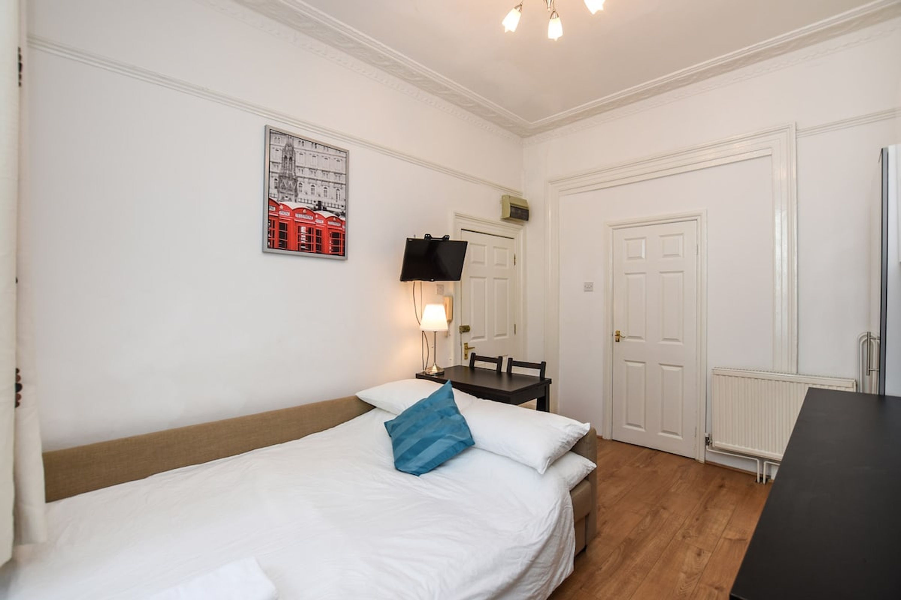 Een hotelkamer met een bed, een bureau, een stoel, een televisie en een deur.