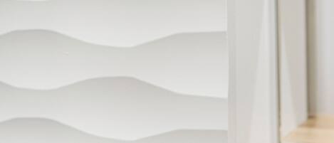 A white, wavy-textured wall with a wooden baseboard.