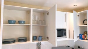 A kitchen with white cabinets, a microwave, and a sink. - Fine Studio Flat - Shepherds Bush Notting Hill (London)