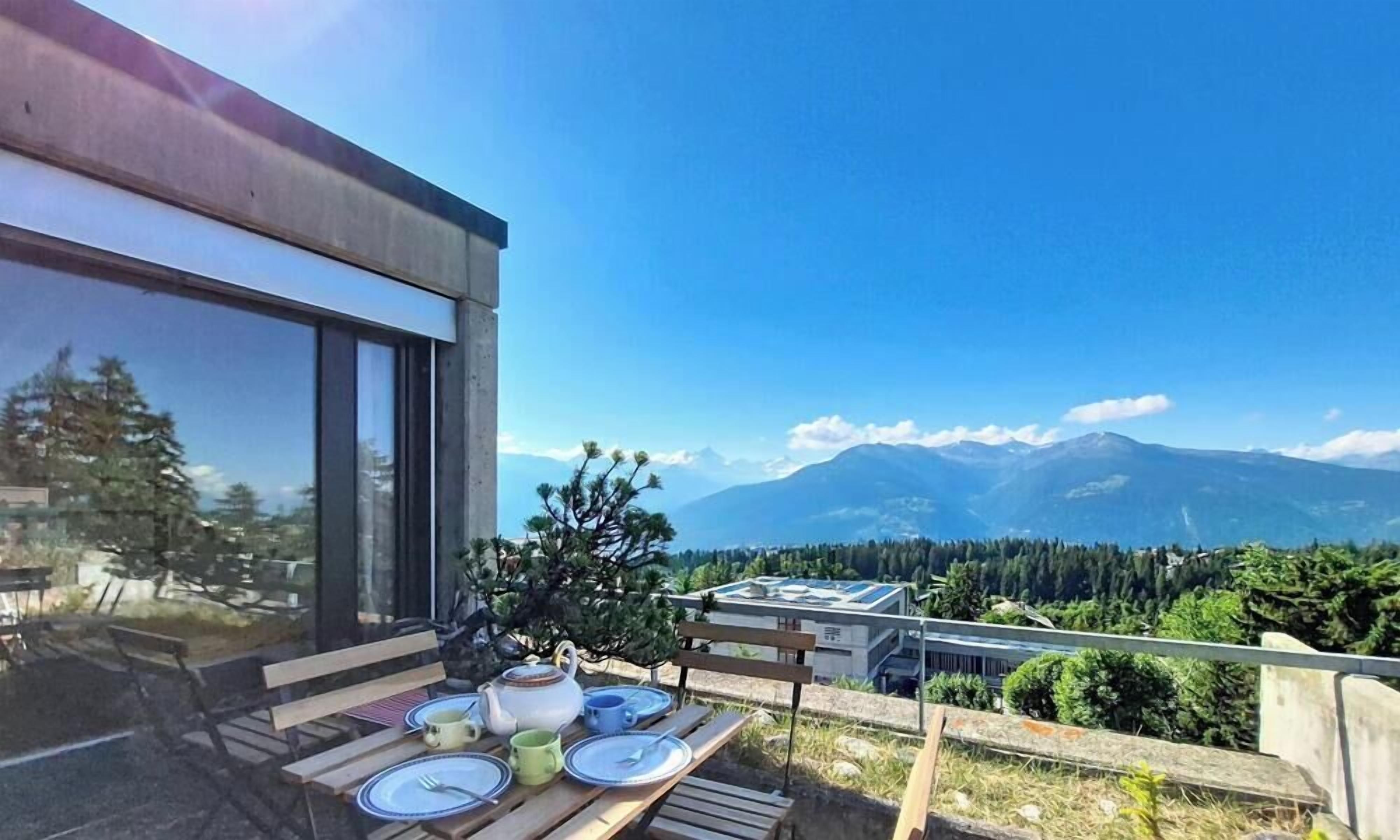Ein Balkon mit Esstisch, der auf eine Berglandschaft blickt.