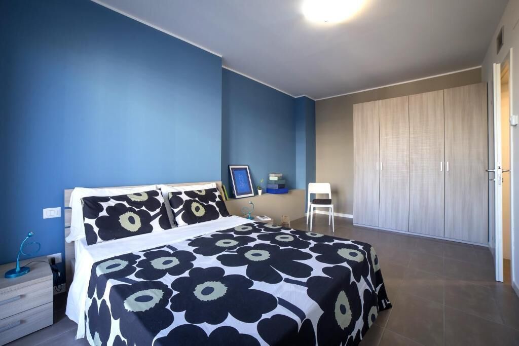 A bedroom with a bed, a desk, a chair, and a wardrobe.