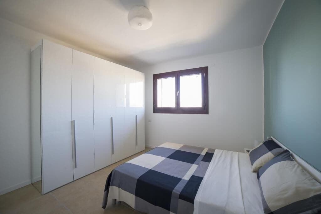 Un dormitorio con cama, armario y ventana.