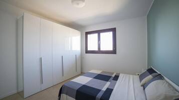 Un dormitorio con cama, armario y ventana.