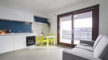 A modern kitchen with white cabinets, a blue backsplash, and a dining area with yellow chairs.