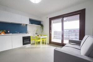 Et moderne køkken med hvide skabe, blå backsplash og et spiseområde med gule stole.