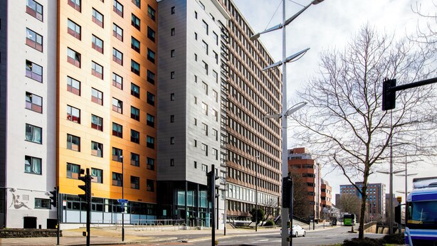 A multi-story building with a modern architectural style, featuring a mix of glass and brick facades, and a visible entrance with a glass door. - Student Only Phoenix Court (Bristol)