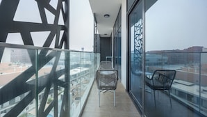 A balcony with two chairs, a table, and a view of buildings. - Bloomfields 2BR in The Gate - Masdar  (Abu Dhabi)