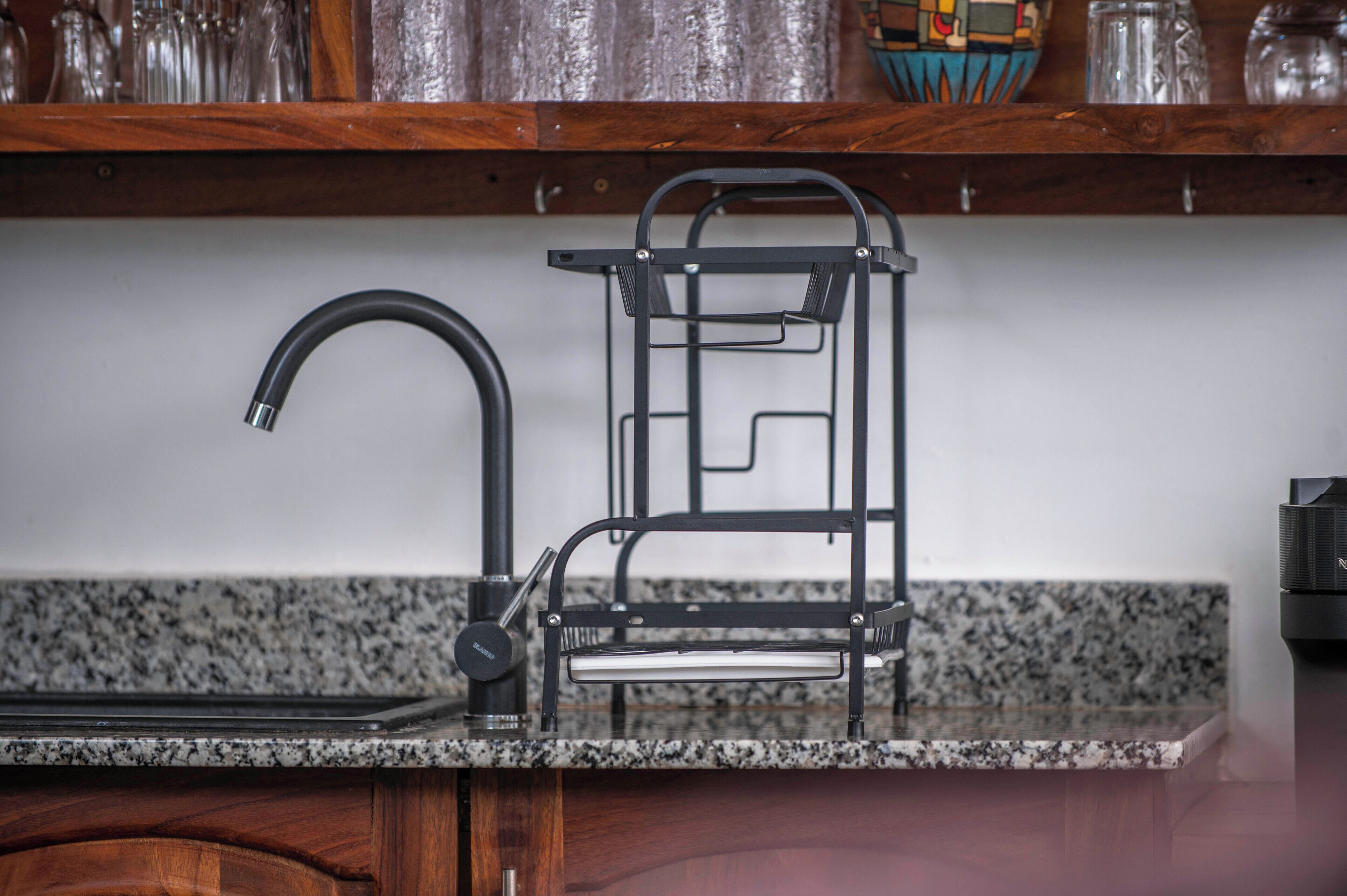 A kitchen with a granite countertop, a black faucet, and a metal drying rack.