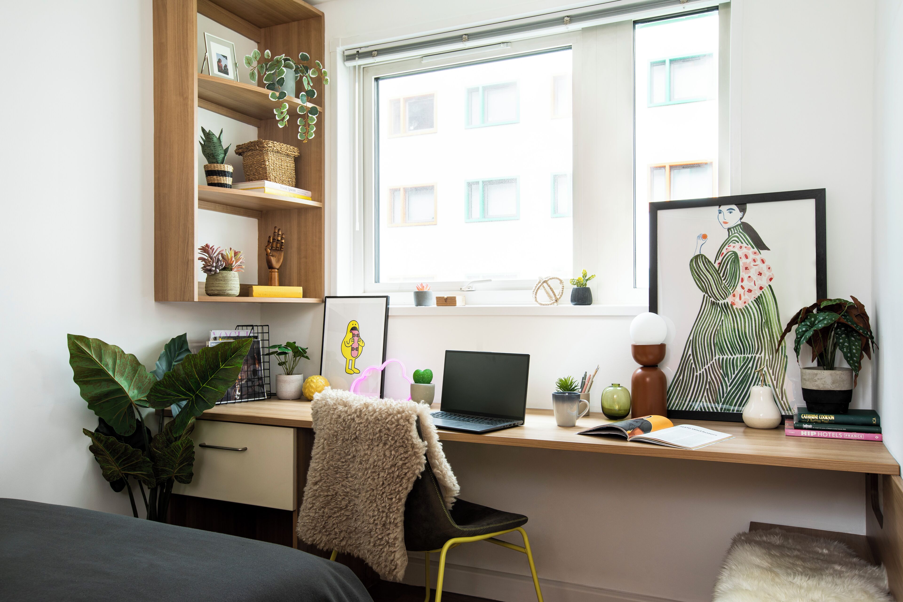 Un espace de travail moderne comprenant un bureau, un ordinateur portable et divers objets décoratifs.