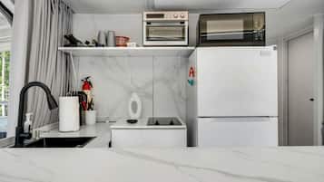 A compact kitchen with a microwave, oven, and a refrigerator.