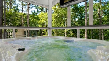 A hot tub in a covered area with a forest view.