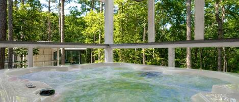 A hot tub in a covered area with a forest view.