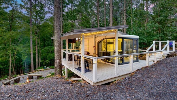 Une cabane dotée d’une terrasse, d’une salle de bain entièrement vitrée et d’un foyer extérieur.