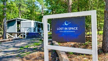 A sign with 'LOST IN SPACE' and 'STELLAR GATEWAYS' text, a small cabin-like structure, and a wooden walkway.