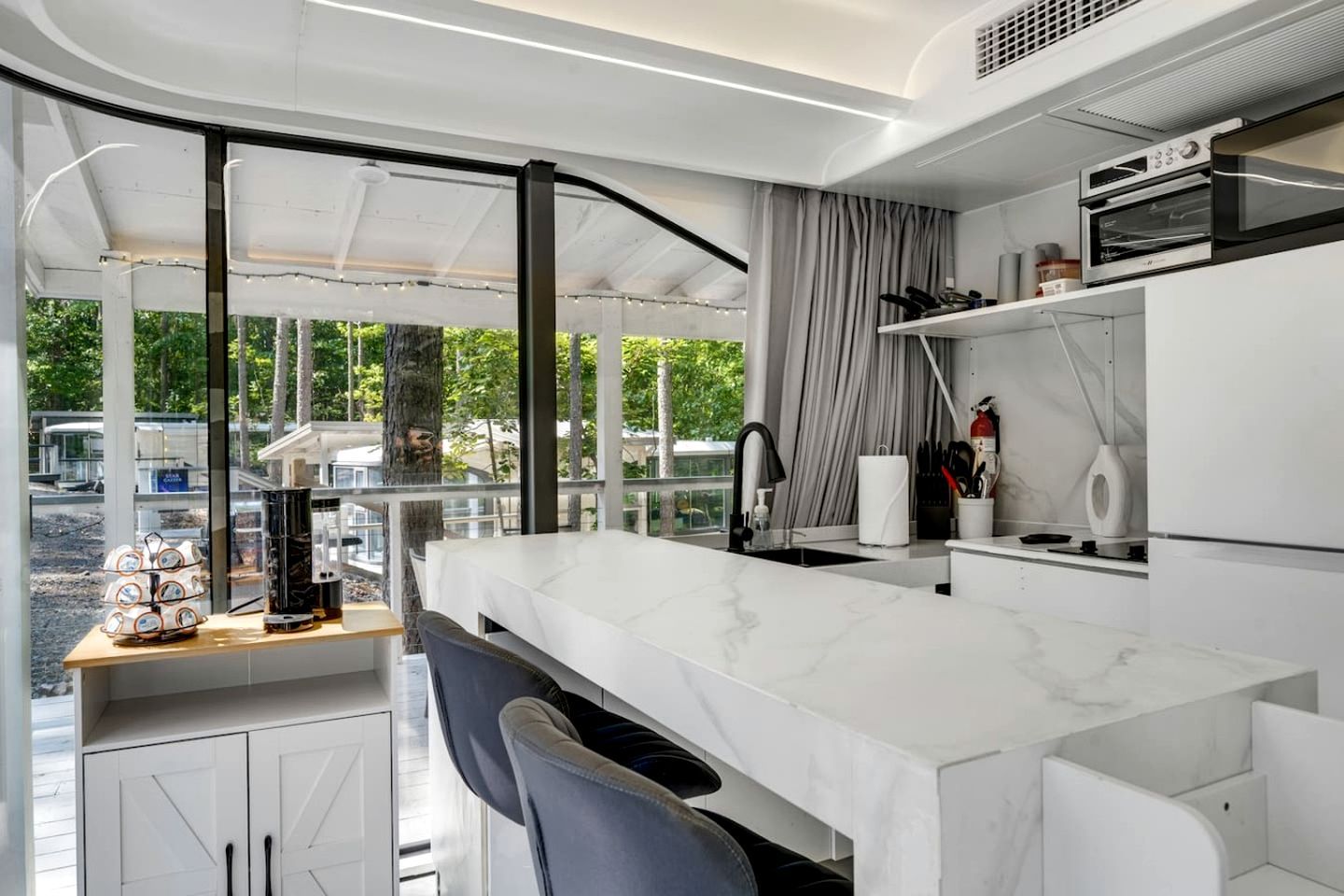 A modern kitchen with a marble countertop, a built-in oven, and a view of the outdoors.