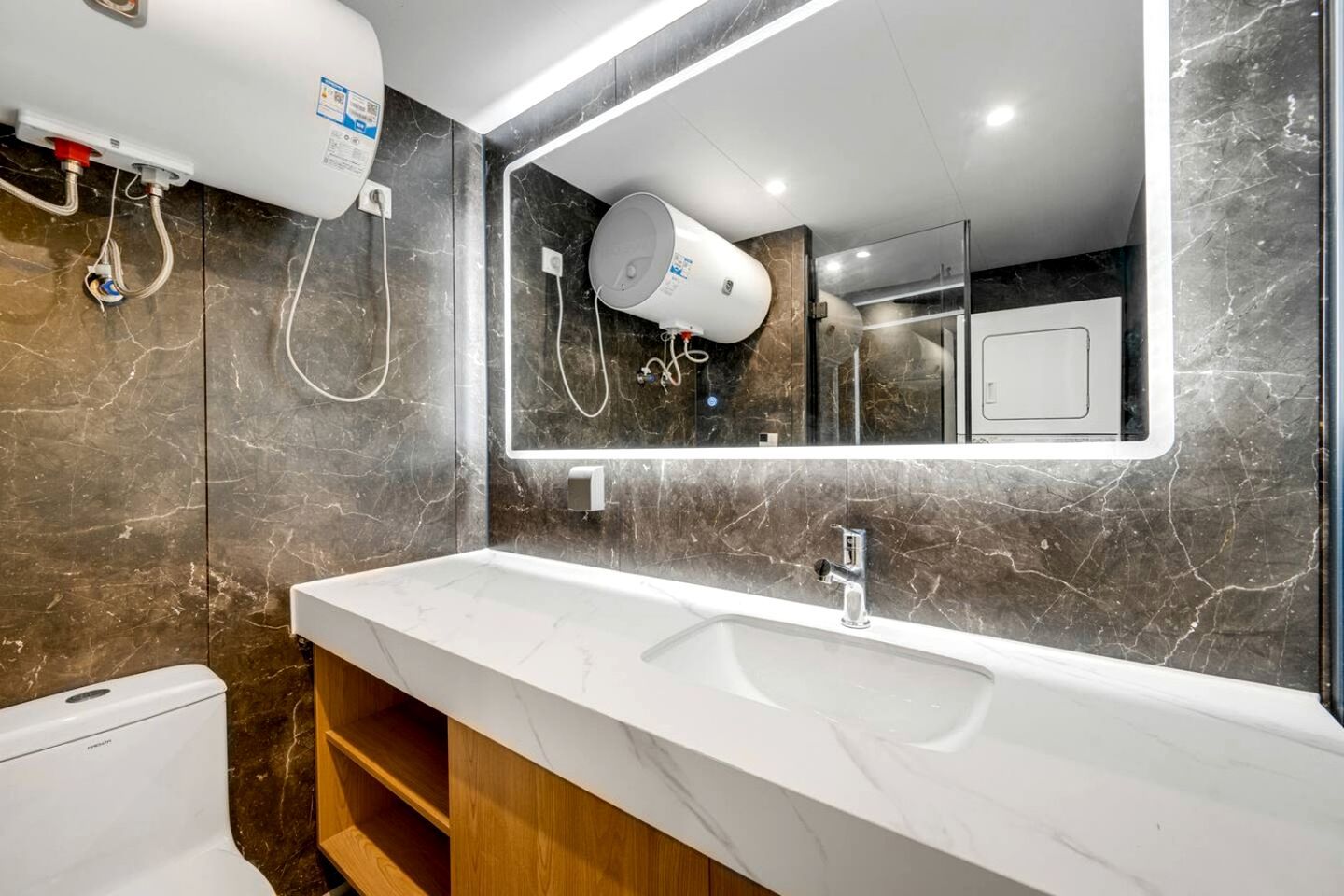 Un baño moderno con un lavabo blanco, un espejo grande y un inodoro.
