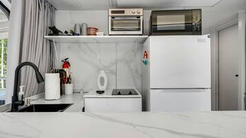 A compact kitchen with a microwave, oven, and a refrigerator.
