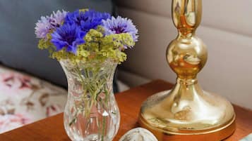 Een glazen vaas met bloemen, een lamp en een boek op een houten tafel.