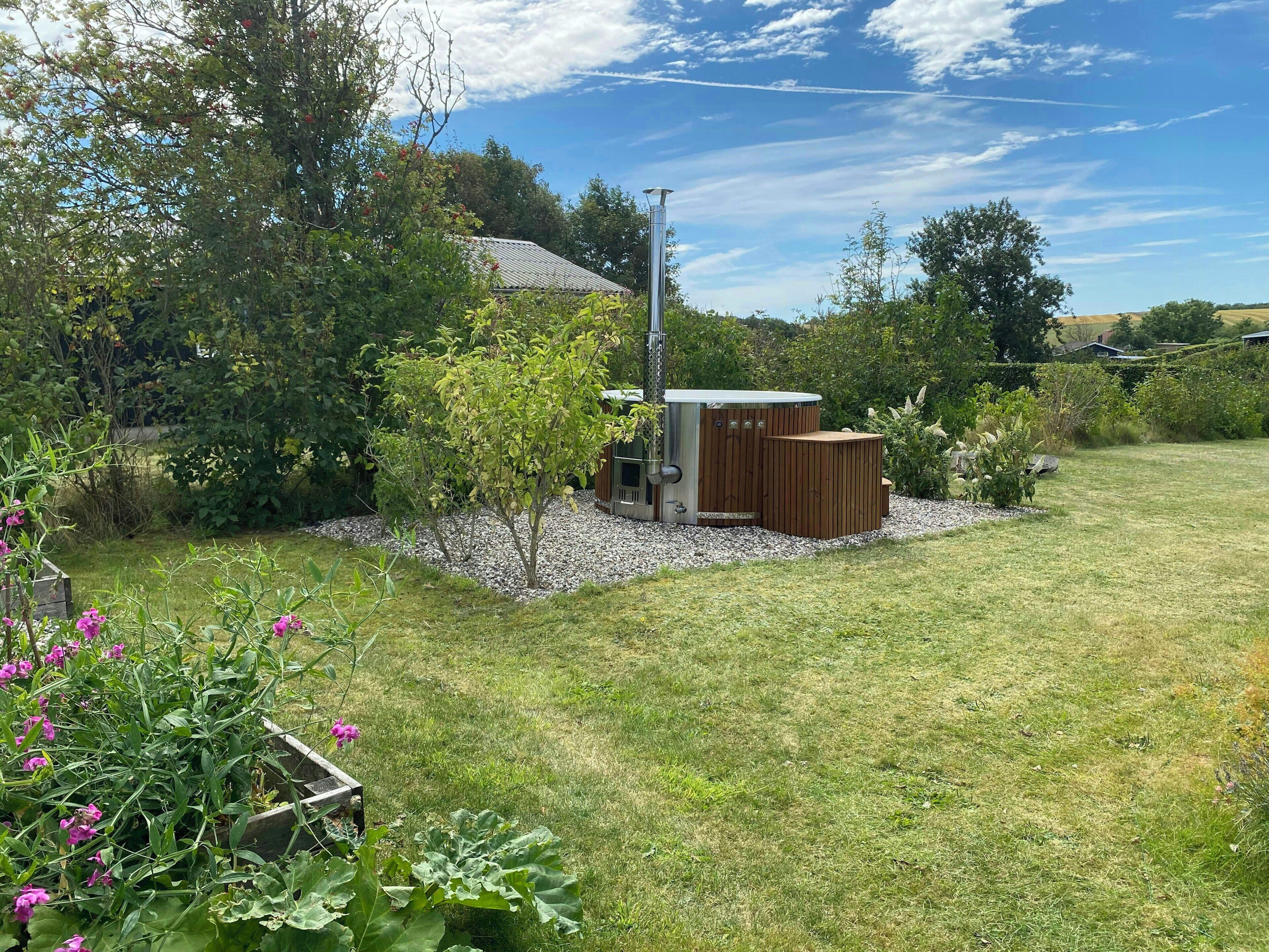 Un jardin avec un petit abri de jardin, une structure métallique et une variété de plantes.