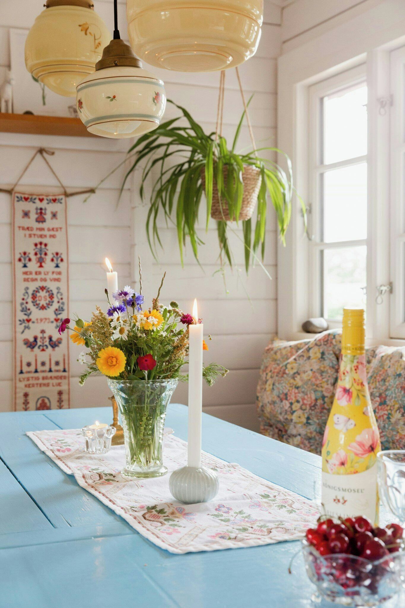 A table with a floral centerpiece, candles, and a bottle of drink.