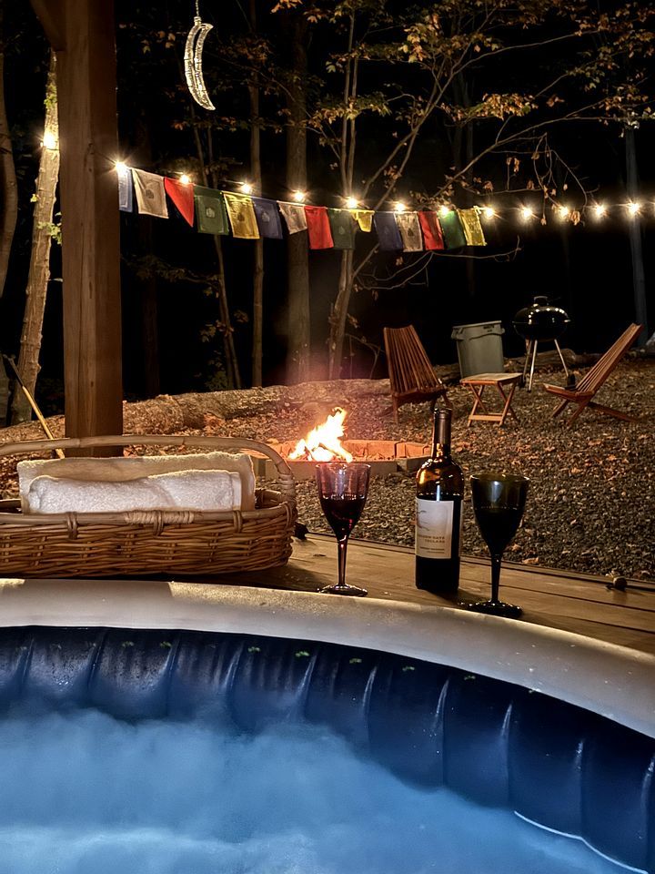 A hot tub with a fire, a bottle of wine, and glasses.