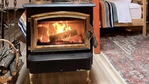 A wood-burning stove in a tent with a bed and a fireplace.