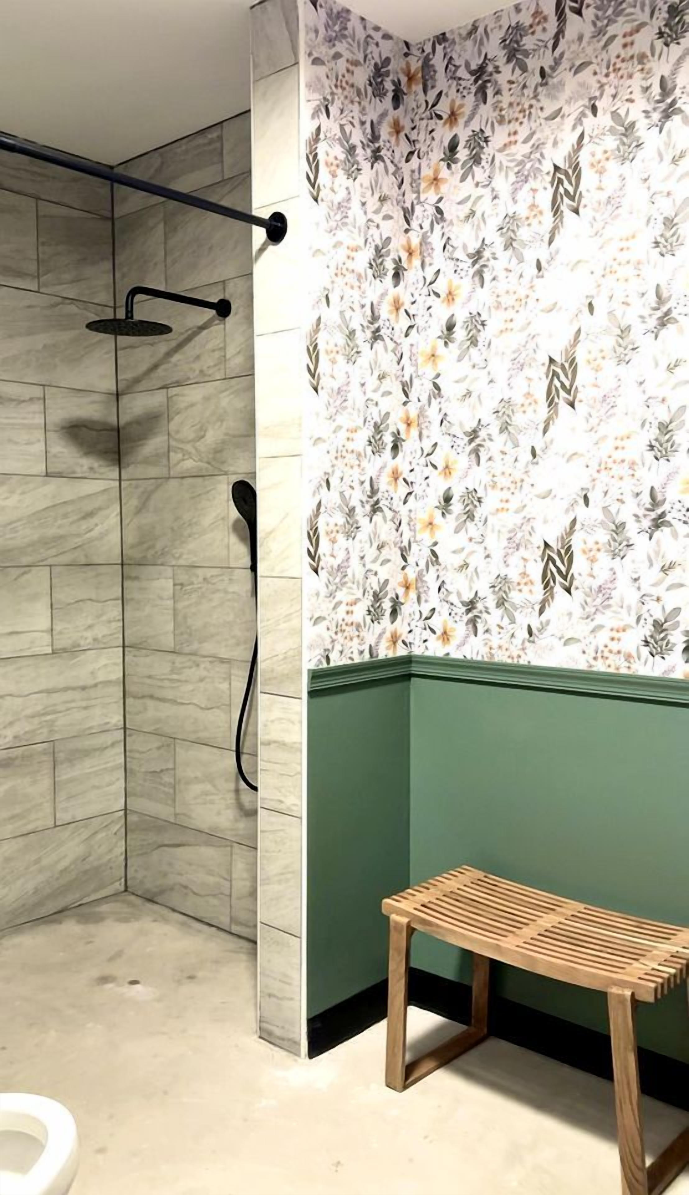 A bathroom with a shower, a toilet, and a bench.