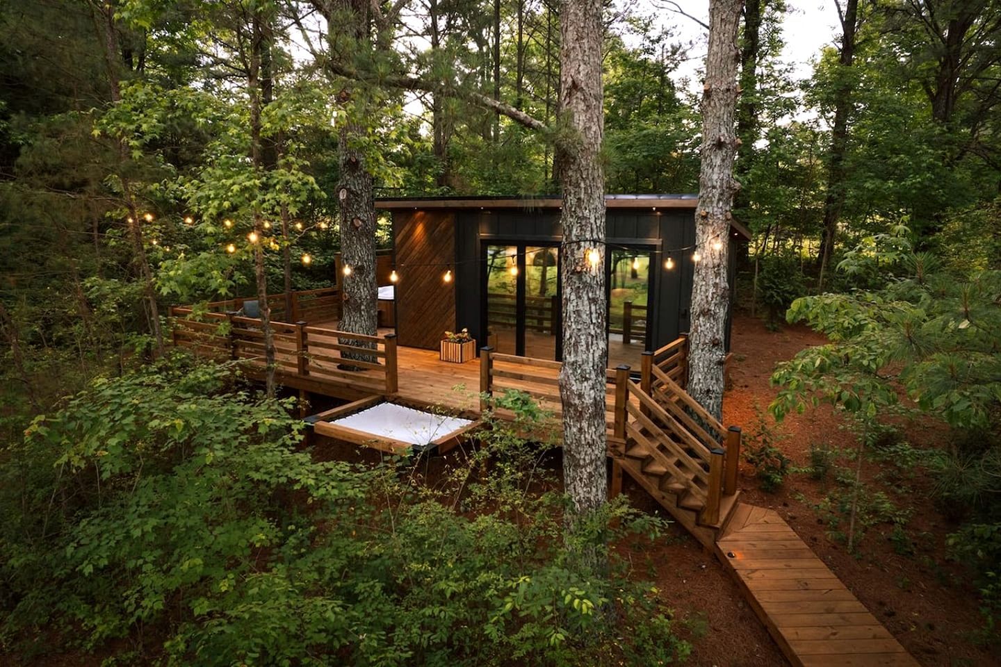 Une cabane dotée d’une terrasse, entourée d’arbres.