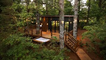 Une cabane dotée d’une terrasse, entourée d’arbres.