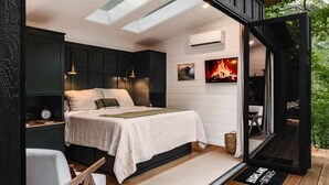 Un dormitorio con cama, mesitas de noche, aire acondicionado de pared y chimenea.