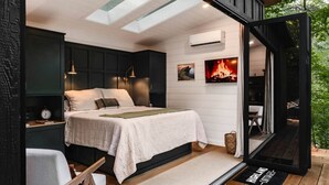 Un dormitorio con cama, mesitas de noche, aire acondicionado de pared y chimenea.