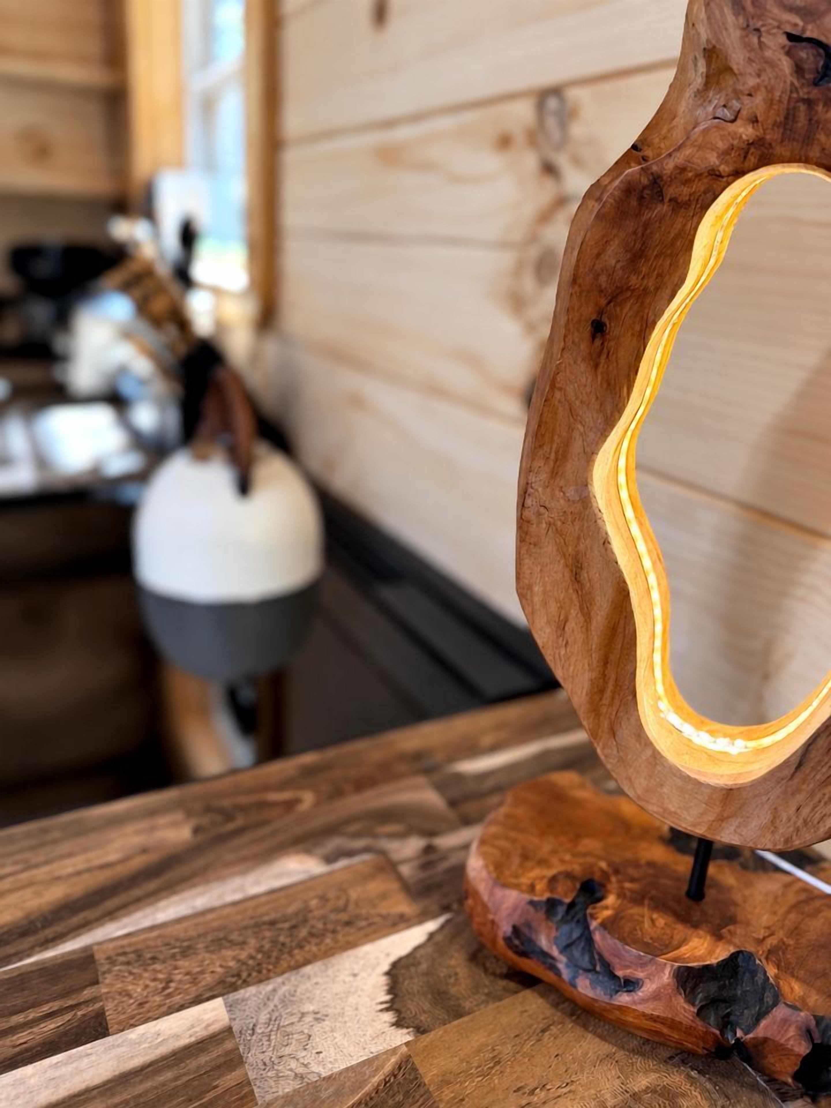 A wooden sculpture with a curved design and a light source inside.