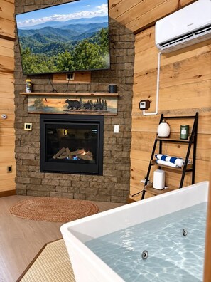 A room with a fireplace, a television mounted on the wall, and a hot tub. - Luxury Romantic Cabin With Hot Tub in Gatlinburg Tennessee Golden Forest Smoky Mountains (Sevierville)