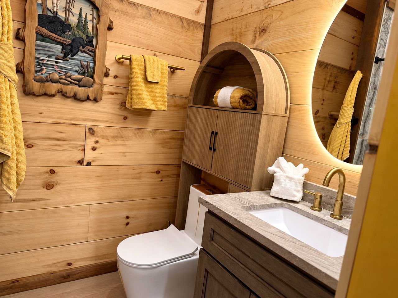 Un baño con paredes de madera, inodoro blanco, lavamanos con grifo dorado y toallero con toallas amarillas.