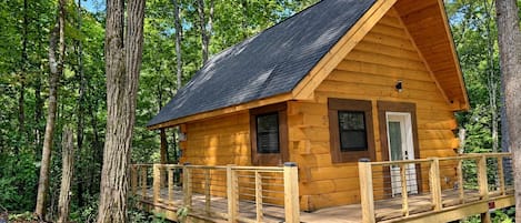 Een houten chalet met een terras, omringd door bomen.