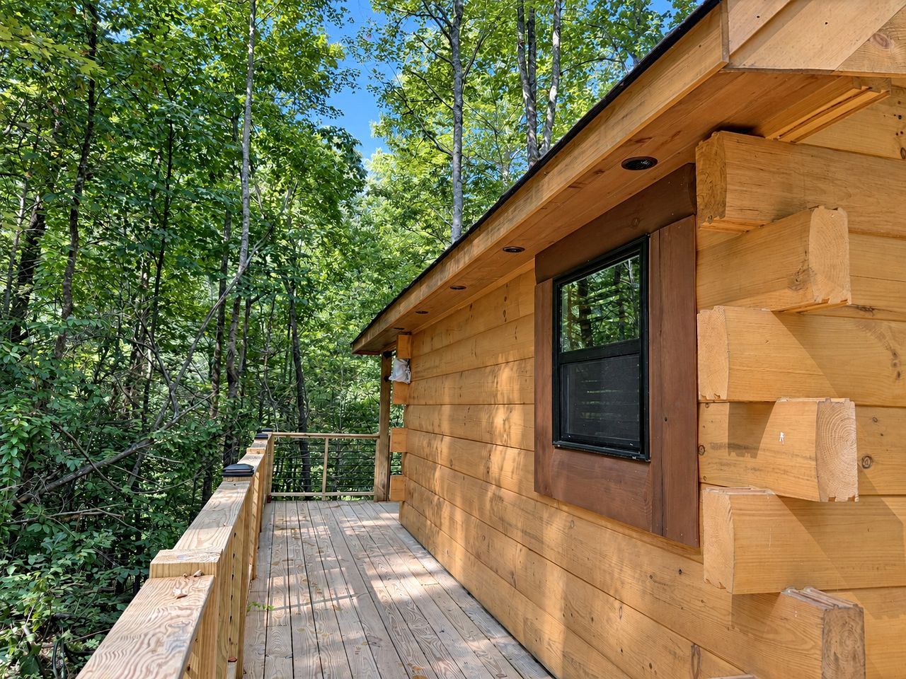 A wooden cabin with a deck, surrounded by trees.