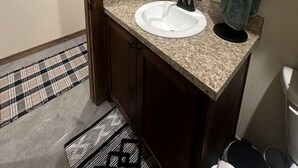 Un baño con lavamanos blanco, espejo, toalla y puerta.