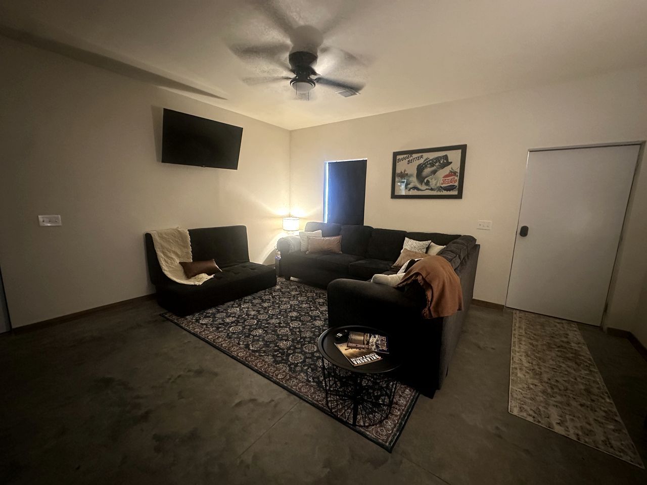 A living room with a ceiling fan, a black sofa, a coffee table, and a patterned rug.