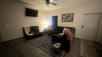 A living room with a ceiling fan, a black sofa, a coffee table, and a patterned rug.