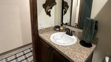 A bathroom with a white sink, a mirror, a towel, and a door.