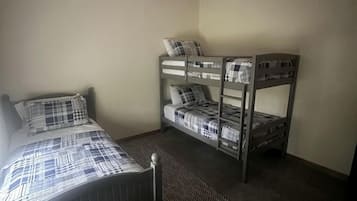 Een slaapkamer met een bed, een stapelbed, een plafondventilator en een vloerkleed.