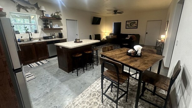 Una cocina compacta con una isla central, taburetes de bar y una mesa de comedor con sillas.