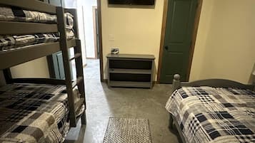 A room with bunk beds, a television, a door, and a small table.