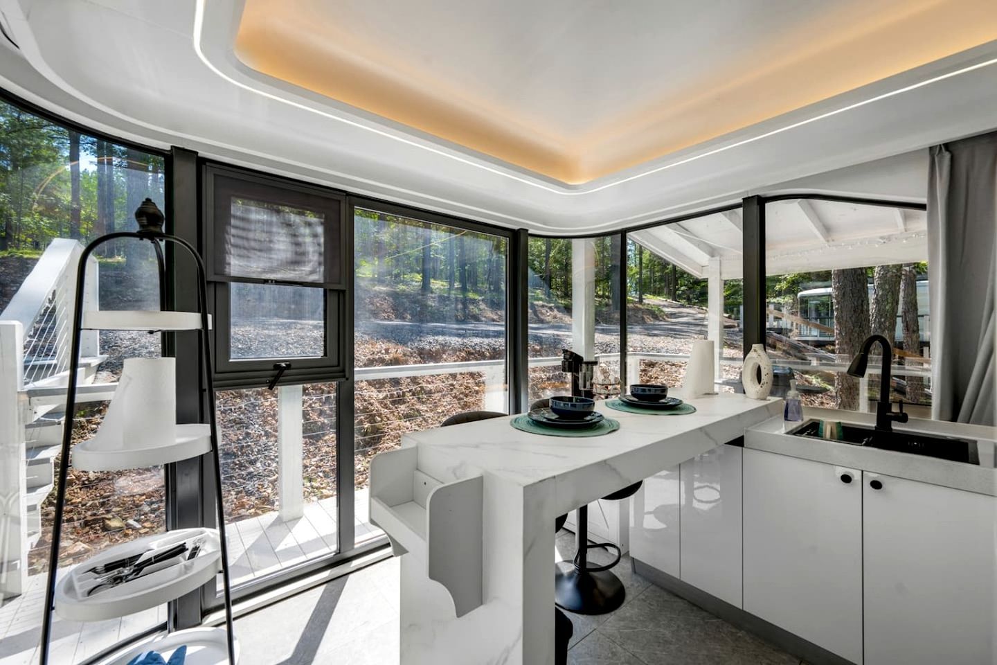 A modern kitchen with large windows, a white countertop, and a sink.
