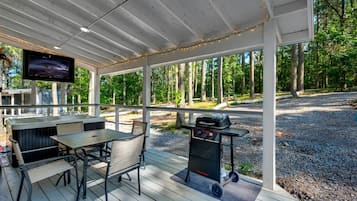 An outdoor deck with a grill, seating, and a TV.
