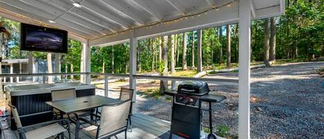 Une terrasse extérieure équipée d’un barbecue, de sièges et d’un téléviseur.