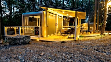 A modern, well-lit cabin with a deck, a TV, and a sign advertising a nearby attraction.